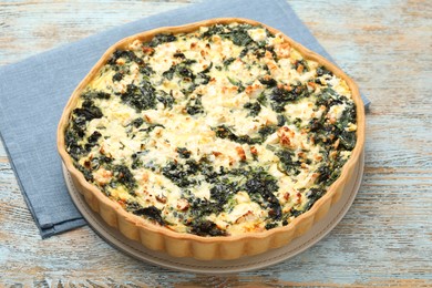 Photo of Delicious homemade spinach quiche on rustic wooden table, closeup