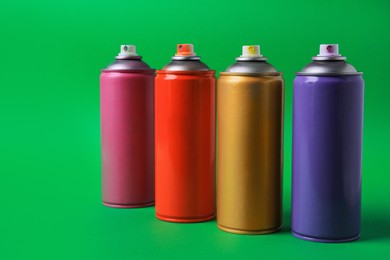 Cans of different graffiti spray paints on green background