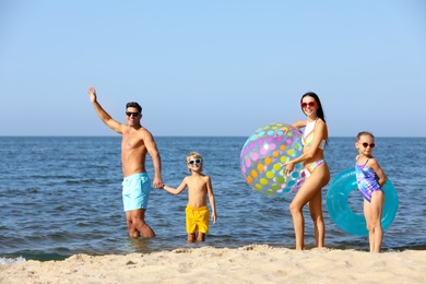 Photo of Happy family with inflatable ball and ring in sea. Summer holidays