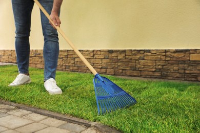Photo of Young man raking grass sods at backyard, closeup