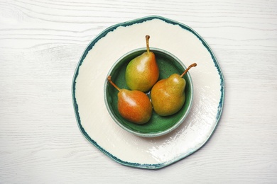 Dishware with pears on wooden background, top view