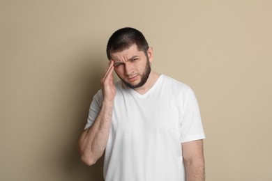 Man suffering from headache on beige background