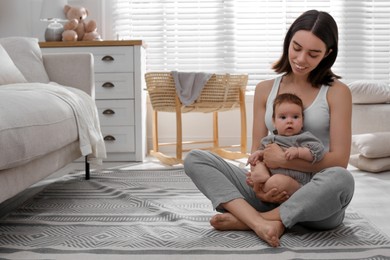 Photo of Young woman with her little baby on floor at home