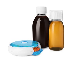 Photo of Bottles of syrups, measuring cup with pills on white background. Cough and cold medicine