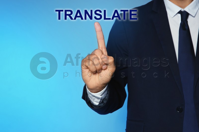Man pointing at virtual model of word TRANSLATE against turquoise background, closeup