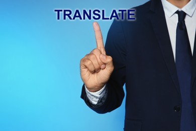 Man pointing at virtual model of word TRANSLATE against turquoise background, closeup