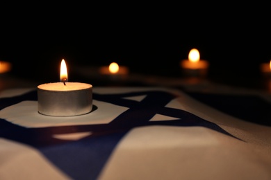 Burning candle on flag of Israel. Holocaust memory day