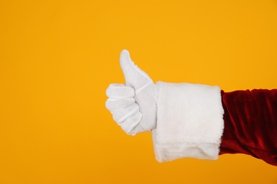 Santa Claus showing thumb up on yellow background, closeup of hand