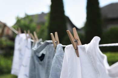 Washing line with clean clothes in garden, closeup. Drying laundry outside