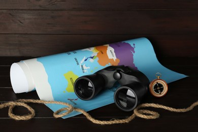 Modern binoculars, rope, compass and map on wooden table