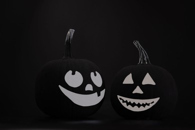 Halloween celebration. Pumpkins with drawn faces on table in darkness