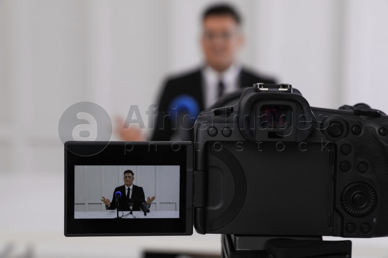 Photo of Business man giving interview at official event, focus on video camera screen