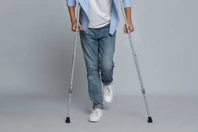 Man with injured leg using crutches on grey background, closeup
