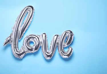 Foil LOVE word balloon on light blue background, top view