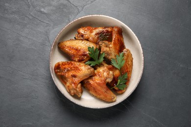 Photo of Bowl with delicious fried chicken wings on black table, top view