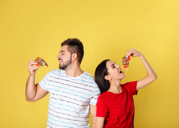 Photo of Young couple with pizza on yellow background
