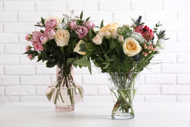 Photo of Beautiful bouquets with fresh flowers on table against white brick wall
