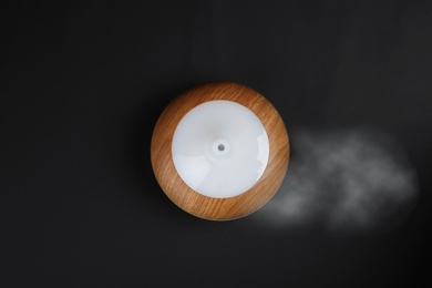 Modern essential oil diffuser on black background, top view
