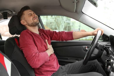 Mature man suffering from heart attack in car