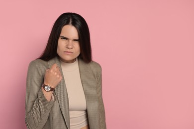 Aggressive young woman on pink background, space for text