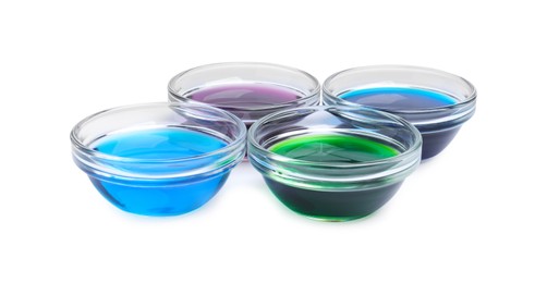 Photo of Glass bowls with different food coloring on white background