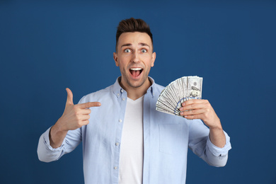 Photo of Emotional man with cash money on blue background