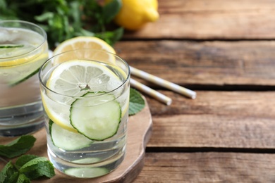 Photo of Refreshing water with cucumber, lemon and mint on wooden table, closeup. Space for text