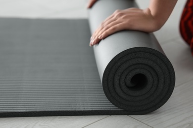 Young woman rolling yoga mat, closeup. Space for text