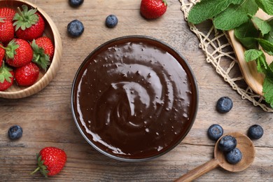 Delicious chocolate cream with berries and mint on wooden table, flat lay