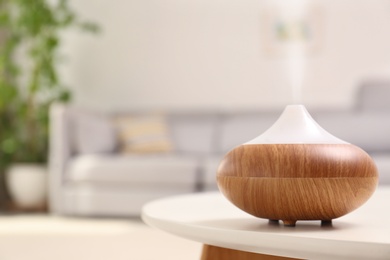 Modern essential oil diffuser on table in room. Space for text