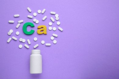 Symbol Ca (Calcium), medical bottle and pills on violet background, top view. Space for text