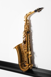 Beautiful saxophone on shelf near white wall. Musical instrument