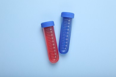Photo of Test tubes with colorful liquids on light blue background, flat lay. Kids chemical experiment set