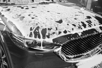 Luxury automobile covered with foam at car wash, closeup