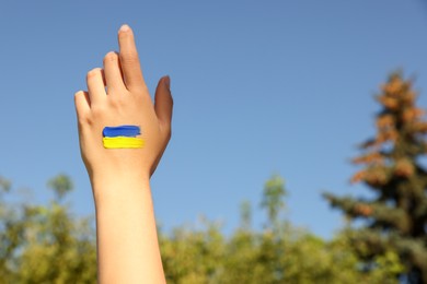 Woman with drawing of Ukrainian flag on hand outdoors, closeup. Space for text