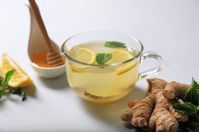 Photo of Delicious ginger tea and ingredients on light grey background
