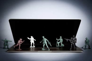 Hybrid warfare concept, online information battle. Laptop and toy soldiers on light grey background