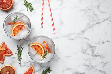 Delicious refreshing drink with sicilian orange and rosemary on white marble table, flat lay. Space for text