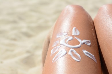Sun drawn with sunscreen on woman's leg at beach, closeup. Space for text