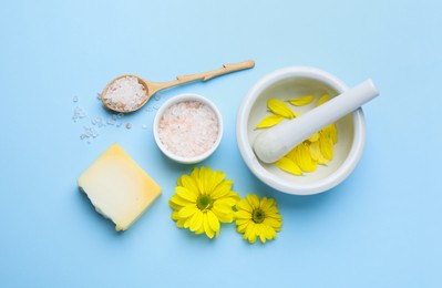 Flat lay composition with beeswax, bath salt and flowers on light blue background