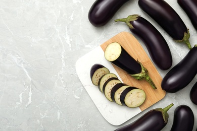 Photo of Cut and whole raw ripe eggplants on grey table, flat lay. Space for text