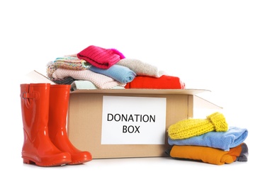 Donation box, rubber boots and clothes on white background