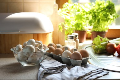 Photo of Fresh mushrooms and carton of eggs on table in kitchen