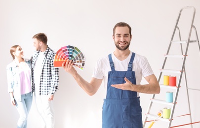 Male decorator with color palette and blurred couple on white background