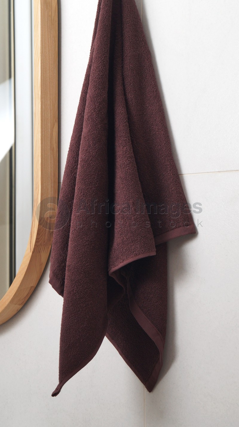 Brown soft towel hanging on grey wall in bathroom