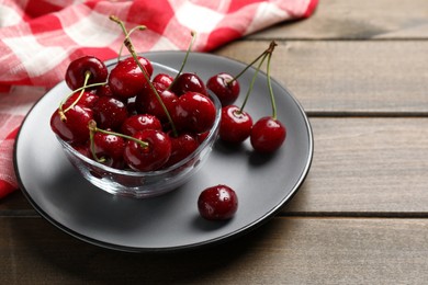 Wet red cherries on wooden table, space for text