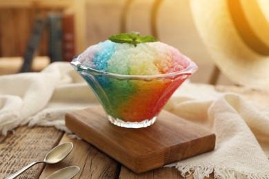 Rainbow shaving ice in glass dessert bowl on wooden  table indoors