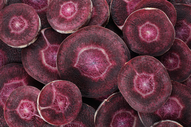 Slices of raw purple carrot as background, closeup
