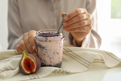 Woman with delicious fig smoothie at white table indoors, closeup