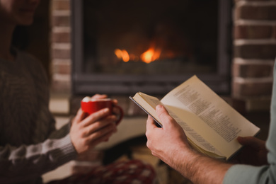 Couple reading book together near fireplace, closeup